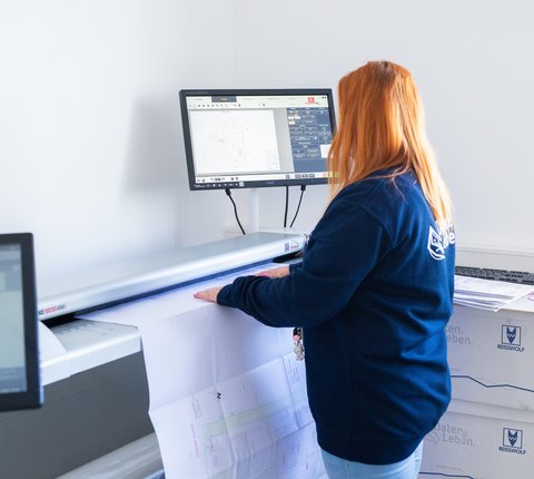 Mitarbeiterin in der Digitalisierung scannt Plan