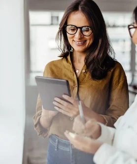 Digitaler Zugriff auf Unternehmensdaten Zwei Frauen betrachten gemeinsam Unternehmensdaten auf einem Tablet und nutzen eine digitale Lösung von REISSWOLF für Datenschutz, Archivierung und Dokumentenmanagement.