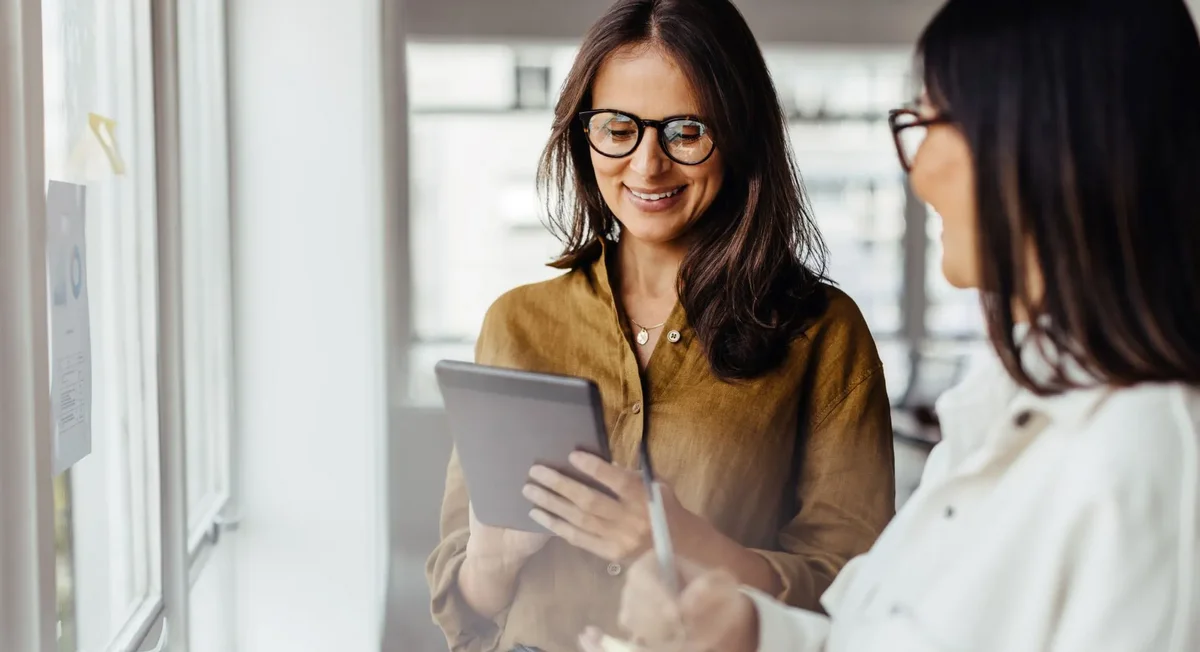 Zwei Frauen betrachten gemeinsam Unternehmensdaten auf einem Tablet und nutzen eine digitale Lösung von REISSWOLF für Datenschutz, Archivierung und Dokumentenmanagement.