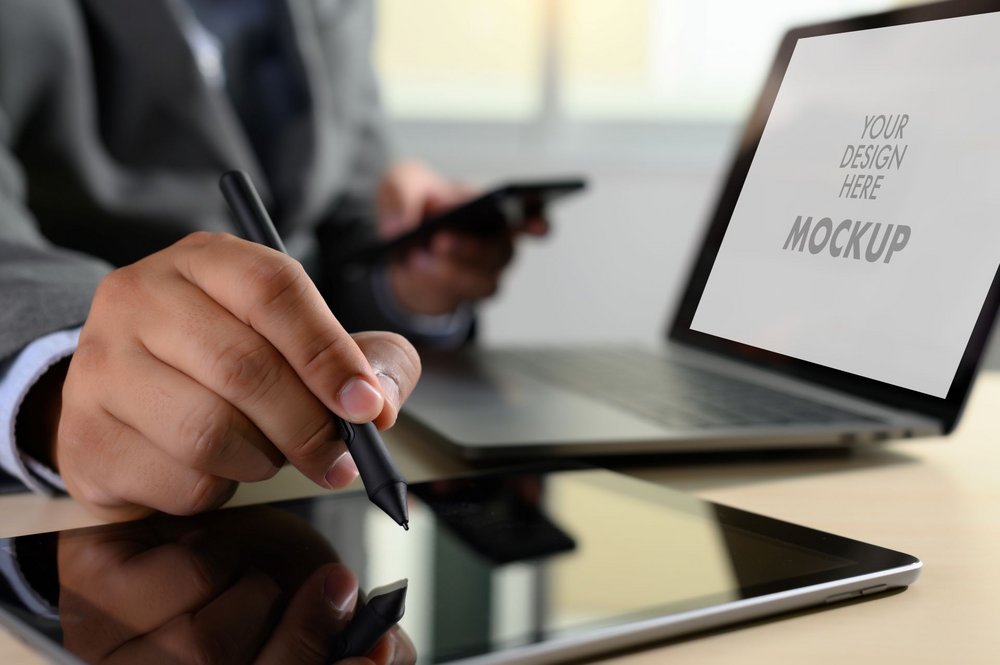 Eine Person sitzt mit einem Stift in der Hand vor einem Laptop.