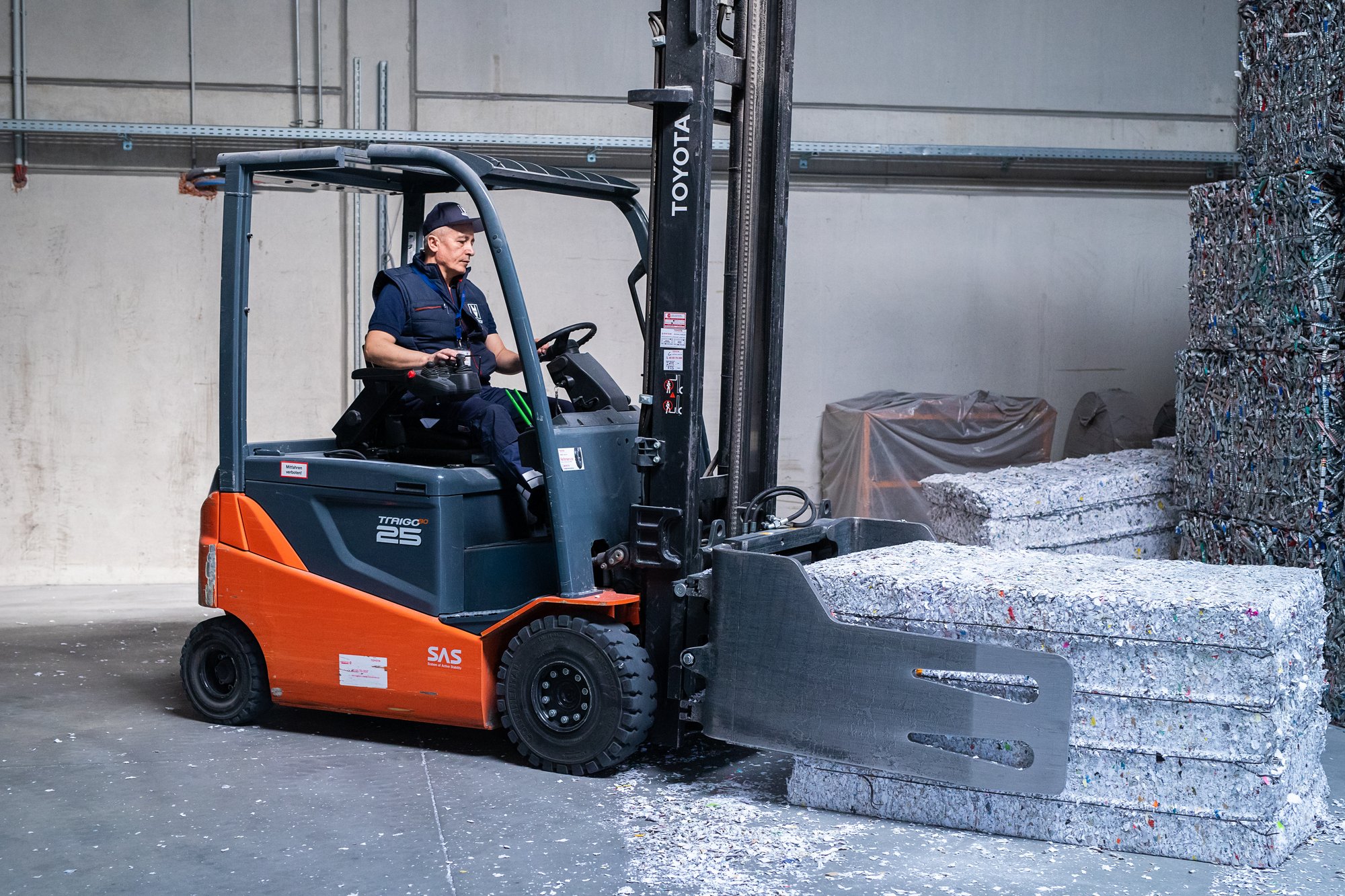 Mitarbeiter in der REISSWOLF Produktion beim Transport von gepresstem Material mit einem Stapler.